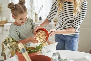 Mother teaching daughter to make compost at home - ABIF01609