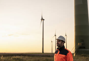 Male inspector wearing hardhat and reflective clothing at sunset - UUF24605