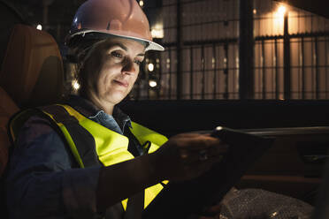 Female professional using digital tablet while sitting in car at night - UUF24609