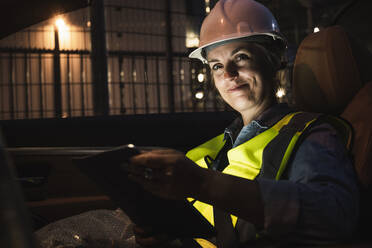 Smiling female engineer with digital tablet sitting in car - UUF24610
