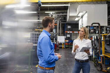 Businesswoman with digital tablet explaining colleague in industry - DIGF16391