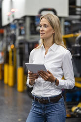Weiblicher Geschäftsmann mit digitalem Tablet in einer Fabrik - DIGF16394