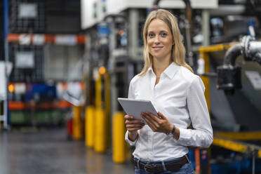 Female professional with digital tablet standing at factory - DIGF16397