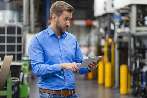 Geschäftsmann mit digitalem Tablet bei der Arbeit in einer Fabrik - DIGF16405