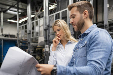 Business professionals brainstorming over plan in factory - DIGF16416