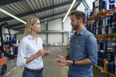 Männlicher Fachmann diskutiert mit weiblicher Kollegin im Lager - DIGF16427