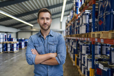 Businessman standing with arms crossed at paint warehouse - DIGF16429