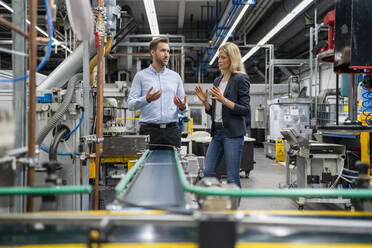 Business professionals having discussion while standing at production line - DIGF16430