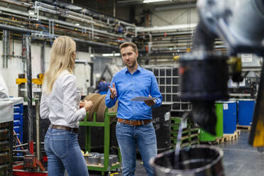 Male professional sharing expertise with female colleague in factory - DIGF16460