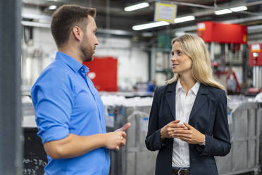 Businessman discussing with female manager at factory - DIGF16482