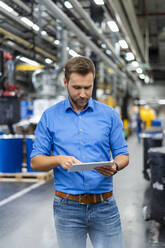 Businessman using digital tablet while standing in factory - DIGF16490