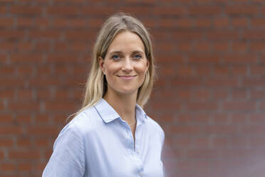 Smiling female business professional in front of wall - DIGF16523