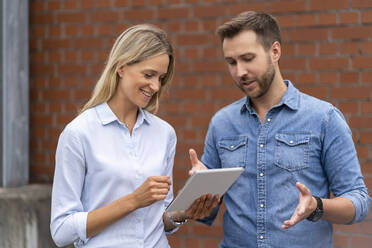 Professionelles Business-Team mit digitalem Tablet vor einer Wand - DIGF16528