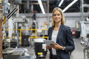 Junge blonde Managerin mit digitalem Tablet in der Industrie - DIGF16538