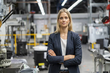 Confident businesswoman with arms crossed at factory - DIGF16541