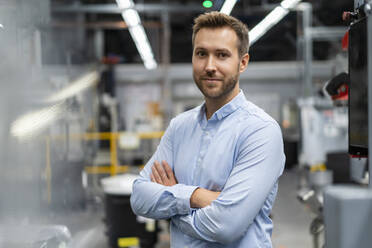 Businessman with arms crossed standing at industry - DIGF16542