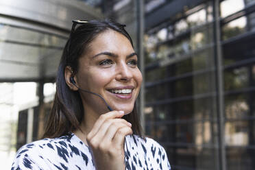 Smiling female freelancer talking through headphones - PNAF02214