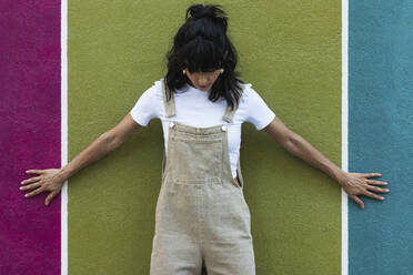 Young woman with arms outstretched leaning on wall - PNAF02233