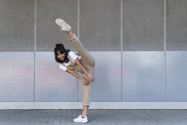 Smiling woman kicking on footpath - PNAF02238