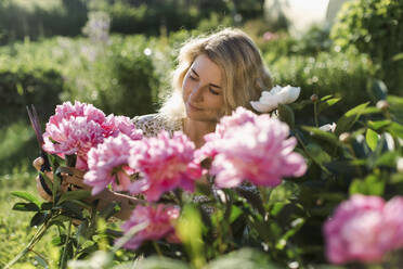 Frau schneidet Blumen im Garten - LLUF00007