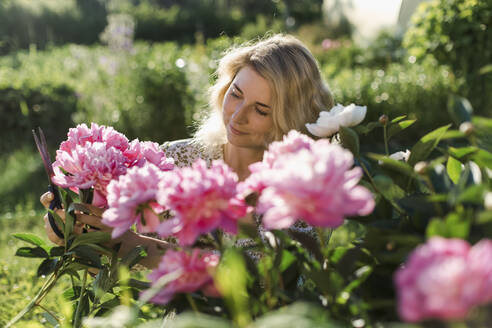 Woman cutting flowers at garden - LLUF00007