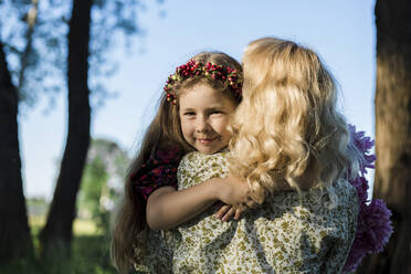 Lächelnde Tochter umarmt Mutter im Garten - LLUF00011