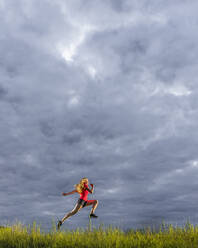 Junge Frau läuft gegen bewölkten Himmel - STSF03036
