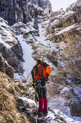 Männlicher Wanderer, der auf einem Felsen stehend den Berg betrachtet, Orobie Alpen, Lecco, Italien - MCVF00889