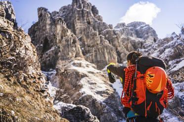 Mann mit Rucksack, der beim Wandern auf einen Berg zeigt, Orobie Alpen, Lecco, Italien - MCVF00890