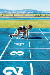 Sportlerin auf dem Lauffeld in Startposition - CAVF94907