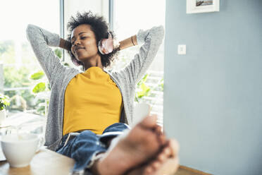 Afro-Frau mit geschlossenen Augen entspannt sich beim Musikhören zu Hause - UUF24675