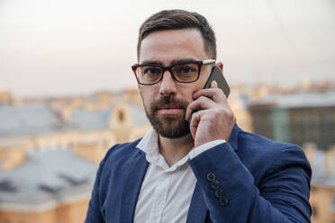 Geschäftsmann mit Brille, der mit einem Smartphone telefoniert - VPIF04782