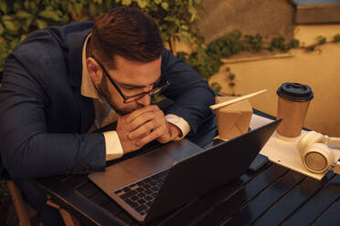 Male professional looking at laptop in office balcony - VPIF04803