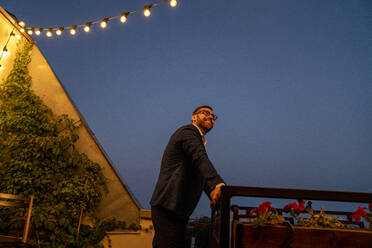 Smiling male professional looking away while leaning on railing - VPIF04810