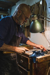 Männlicher Handwerker, der in einer Werkstatt Holz bearbeitet - JCMF02229