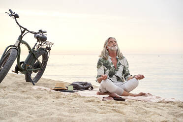 Mann übt den Lotussitz beim Meditieren am Strand - VEGF04975