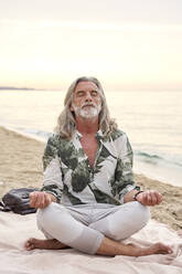 Man with gray hair meditating at beach - VEGF04976