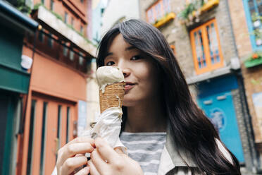 Young woman with ice cream cone in front of buildings - ASGF01500