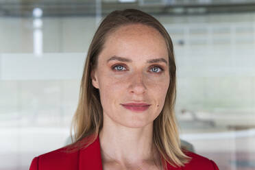 Blond businesswoman in front of glass wall - PNAF02281