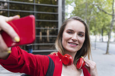 Blonde Geschäftsfrau nimmt Selfie durch Mobiltelefon - PNAF02297