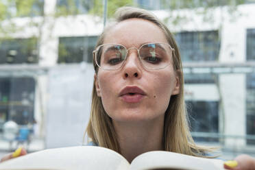 Blond businesswoman with eyeglasses reading book - PNAF02314