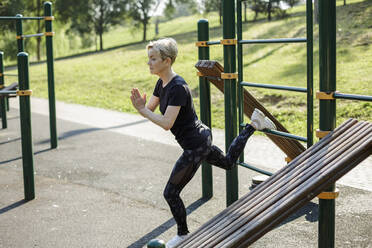 Woman with hands clasped exercising at park - LLUF00040