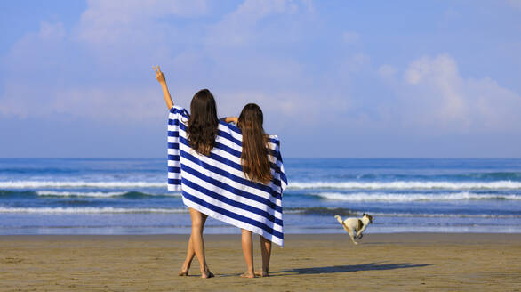 Women wrapped in towel gesturing at beach - EAF00124