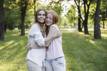 Mid adult woman hugging daughter at public park - LLUF00052