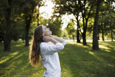 Woman with long hair looking away at public park - LLUF00053