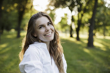 Beautiful woman with brown hair smiling at park - LLUF00054