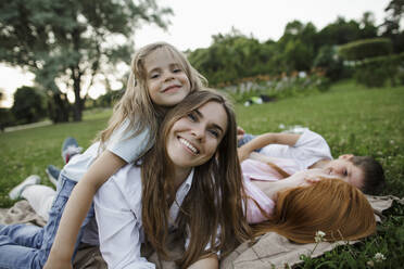 Girl embracing mother by siblings at public park - LLUF00058