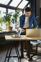 Male professional smiling during video conference through laptop in office - BSZF01945