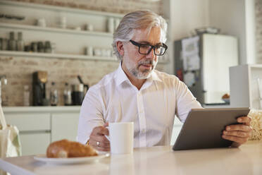 Geschäftsmann mit digitalem Tablet bei einem Kaffee in der Büro-Cafeteria - RBF08307