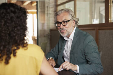 Bearded male professional explaining business plan to female colleague in office - RBF08370
